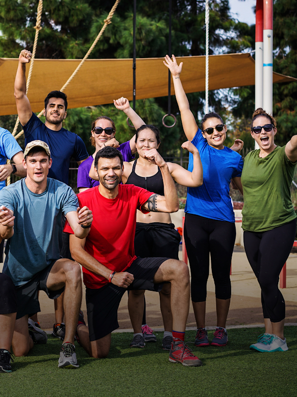 Nineteen people wearing athletic apparel smile and pose for a group picture