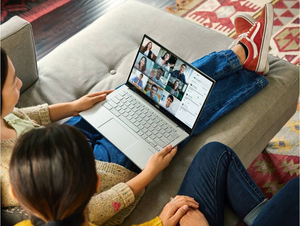 Dua perempuan duduk di sofa yang sama berpartisipasi dalam rapat Google Meet