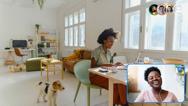 Seorang wanita bekerja dengan laptop di rumah, sambil terhubung secara virtual dengan teman dan kolega