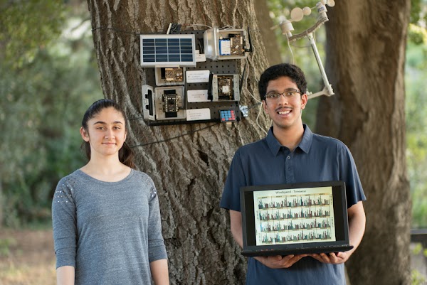 นักเรียน Aditya Shah และ Sanjana Shah ยืนอยู่หน้าอุปกรณ์เซ็นเซอร์ตรวจจับไฟป่าอัจฉริยะที่ทำงานด้วยระบบ AI