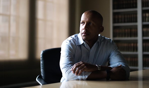 Bryan Stevenson ผู้อำนวยการบริหารแห่ง Equal Justice Initiative รูปภาพชายผิวดำหัวล้านสวมเสื้อเชิ้ตกำลังนั่งอยู่ที่โต๊ะ