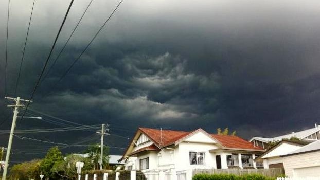 Storm clouds roll in over the Brisbane suburb of Annerley. A white house in the foreground stands out against the dark sky.