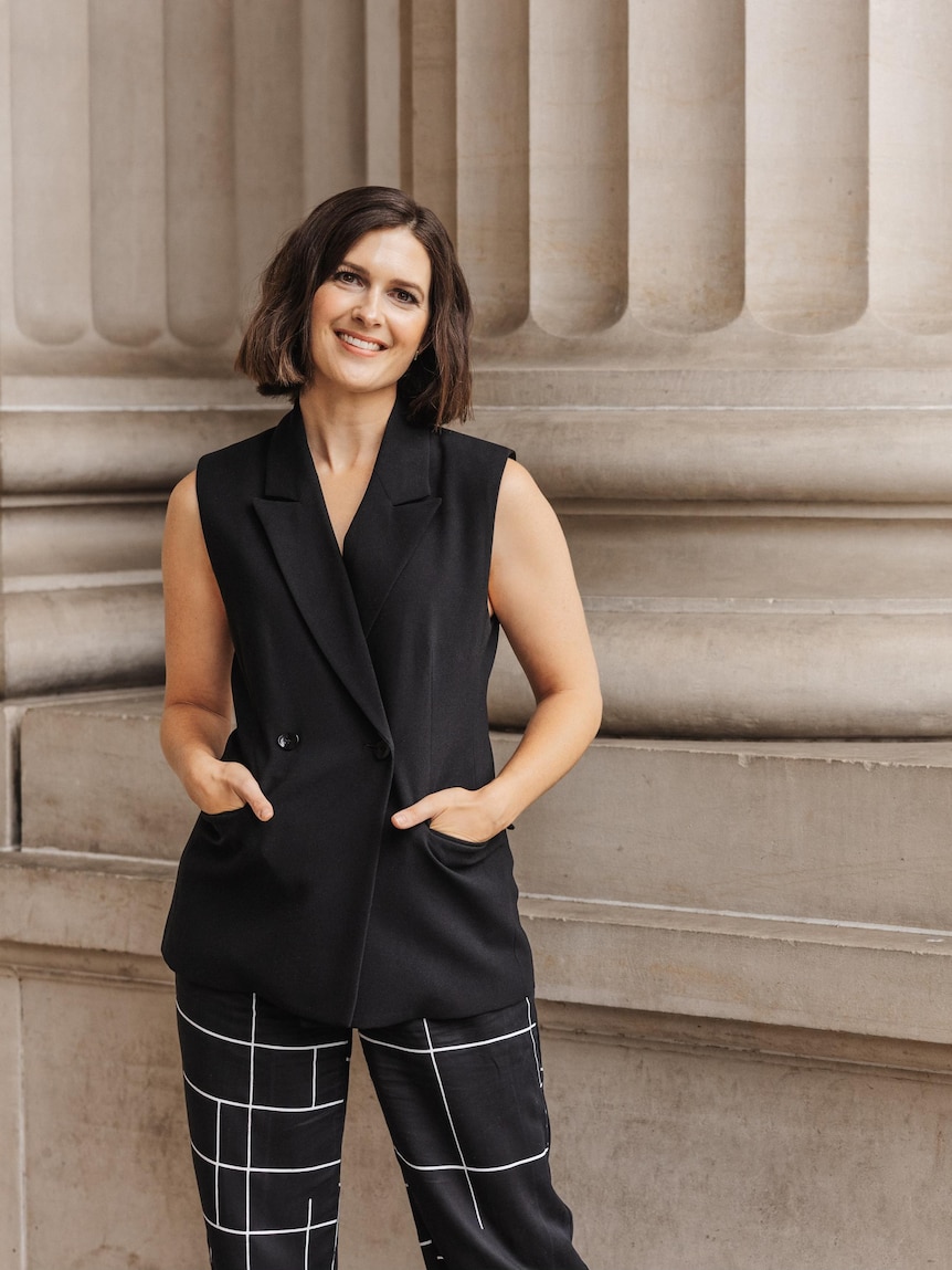 Financial planner Rebecca Pritchard smiles for a portrait. Her hands are in her pockets.