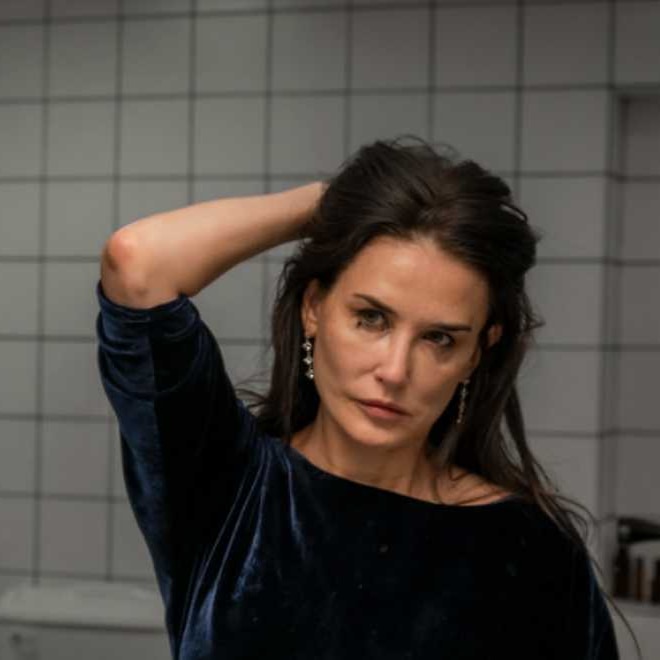 A scene from the film 'The Substance' in which Demi Moore looks into a mirror and frowns 