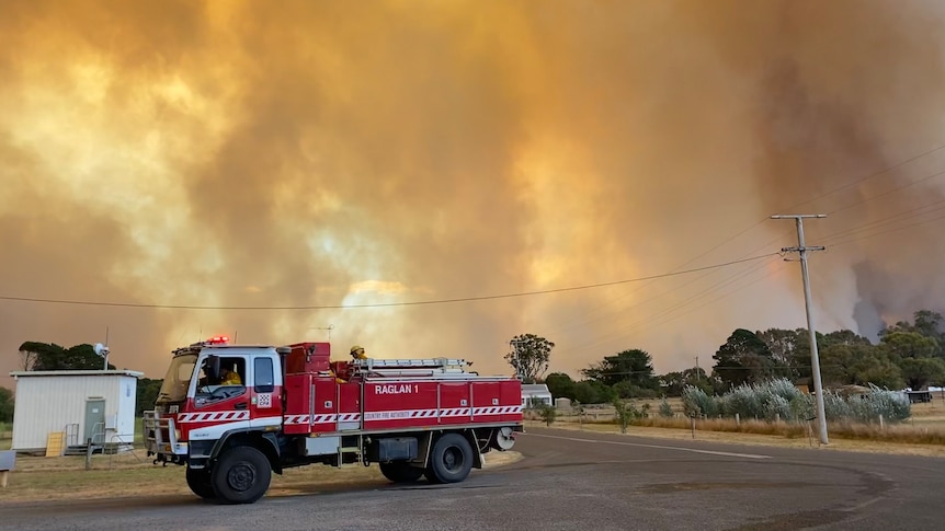 A red fire truck parked on a road beneath power lines under a smoky yellow sky 