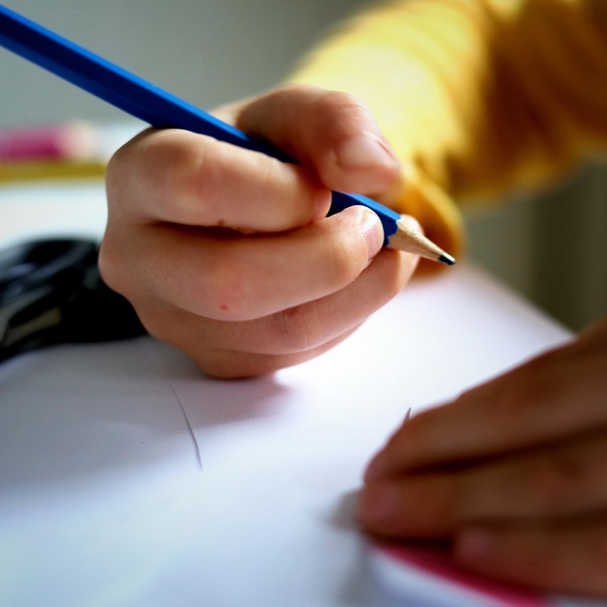 a child's hand holds a pencil.