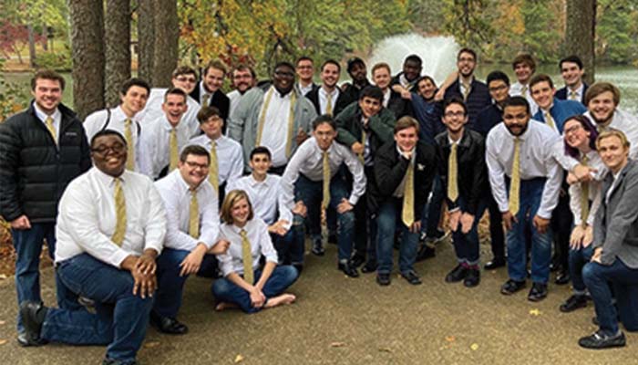 Glee club takes a photo outside in the forest