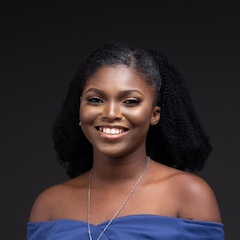 A young woman wearing a necklace and dress smiling at the camera.