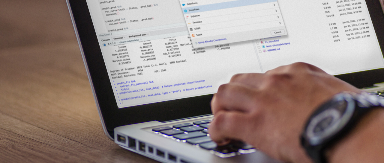 Close up of a person working on their laptop with RStudio Pro on the screen