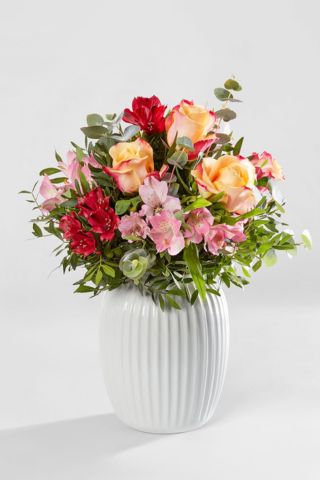 Romantischer Blumenstrauss mit Rosen, Eukalyptus und Alstromerien in einer Vase vor einem hellen Hintergrund. Bei SayFlowers bestellen.