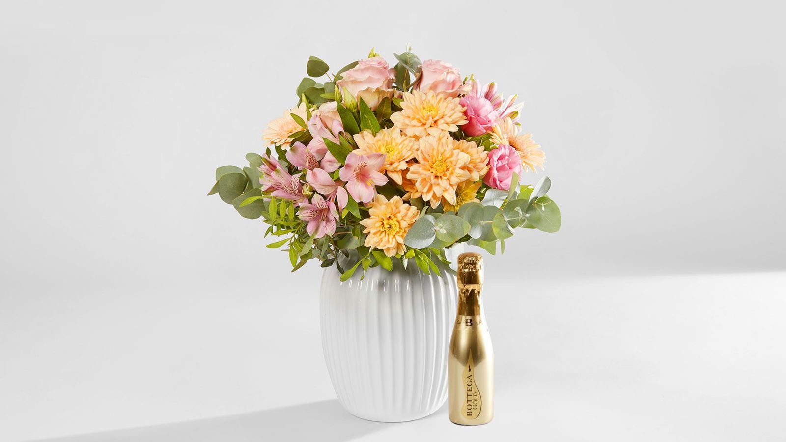 Pastellfarbener Blumenstrauss in einer Vase vor einem weissen Hintergrund, Bundle mit Mini-Prosecco Gold online bestellen und schweizweit verschicken.