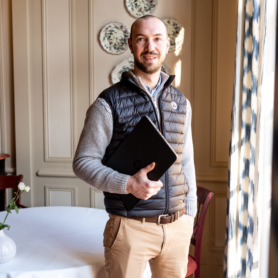 Bernard Giraudev est debout près d'une fenêtre dans son hôtel restaurant et tient dans ses mains le registre de l'hôtel.